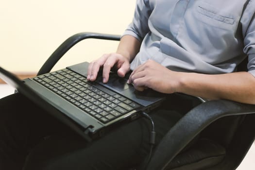 Adult man sit and typing laptop on your leg in home office .