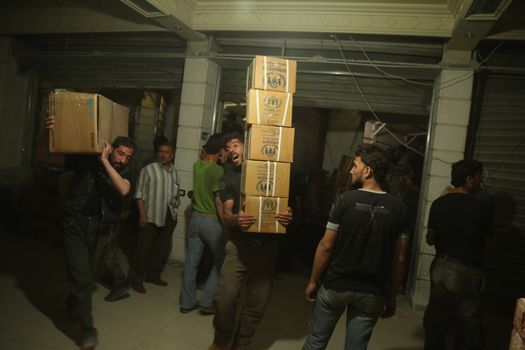 SYRIA, Saqba: Men unload Syrian Arab Red Crescent lorries carrying aid sent by the United Nations in the town of Saqba, in the eastern Ghouta area, a rebel stronghold east of the Syrian capital Damascus, on April 19, 2016.
