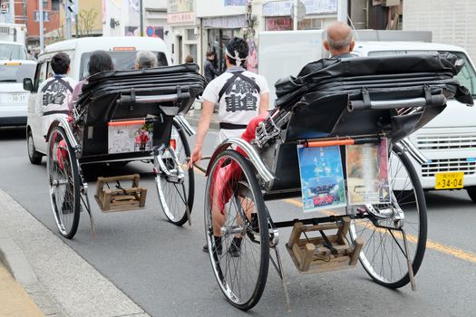 TOKYO, JAPAN - MARCH 30 2016: Tourists take a rickshaw ride to explore the city around Senso-ji Temple in Asakusa on March 30 2016. The Rickshaws are a popular way to tour the city.