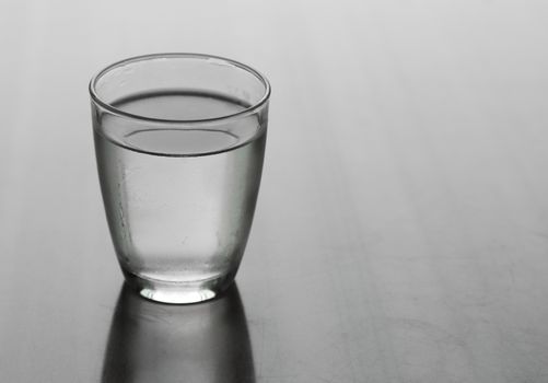 Glass of water on a reflective table top