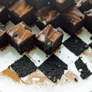 Cake chocolate brownies on white plate with leavings of brownies