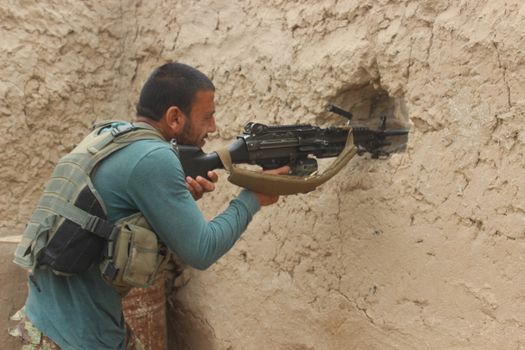 AFGHANISTAN, Alchin: A man fires behind a wall as soldiers of Afghan national army (ANA) fights back Taliban militants in Alchin village, in Kunduz province, in northern Afghanistan on April 16, 2016. Afghan security forces drove Taliban fighters back from Kunduz city, officials said, as the insurgents began the 2016 fighting season by targeting the northeastern provincial capital they briefly captured last year. At least 64 people were killed and hundreds wounded when a Taliban truck bomb tore through central Kabul and a fierce firefight broke out on April 19, 2016 one week after the insurgents launched their annual spring offensive. The brazen assault near the defence ministry marks the first major Taliban attack in the Afghan capital since the insurgents announced the start of this year's fighting season. (The photographer is embedded with ANA)  