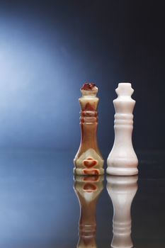 Pair of chess Kings made from Onyx on board against dark background