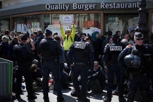 FRANCE, Paris : Demonstrators part of the Nuit Debout movement face police officers during a protest against split shifts and to demand wage increases in front of a fast food restaurant in Paris on April 20, 2016. 