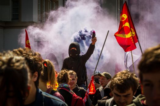 FRANCE, Strasbourg: A protester holds a smoke grenade during a demonstration in Strasbourg, on April 20, 2016, against the French government's proposed labour law reforms. 