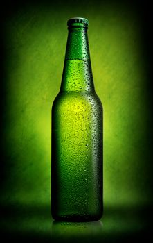 Delicious beer in bottle on green background