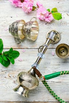 Stylish metal Arabic hookah, and small flowers of wild rose