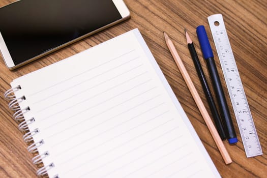 Blank note book with pencil pen and smartphone on wood table concept and Idea for write your text here.