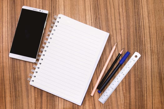 Blank note book with pencil pen and smartphone on wood table concept and Idea for write your text here.