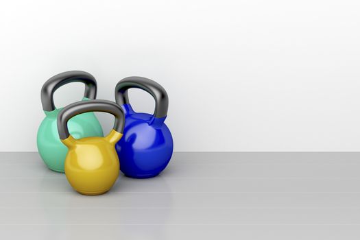 Three kettlebells of different size on shiny gray floor in the fitness center