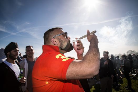 UNITED-KINGDOM, London: A man smokes a large reefer as hundreds of pro-cannabis supporters gather in Hyde Park, in London for 4/20 day, a giant annual smoke-in  on April 20, 2016. 