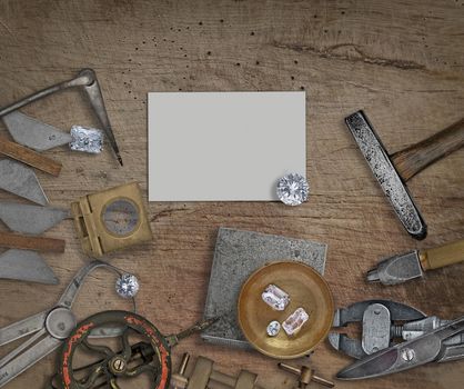 vintage jeweler tools and diamonds on a bench, space for text on business card