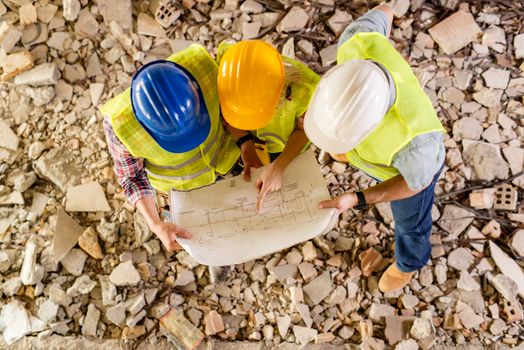 Three construction architects review plan in building damaged in the disaster.