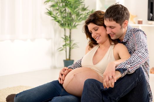 Portrait of a beautiful young couple cuddling the woman's pregnant belly. 