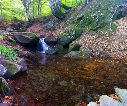 Waterfall in the Carpathian autumn forest. Water with motion blur.