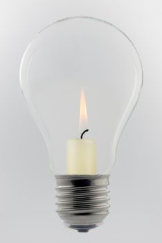 Conceptual glass light bulb with burning candle inside
