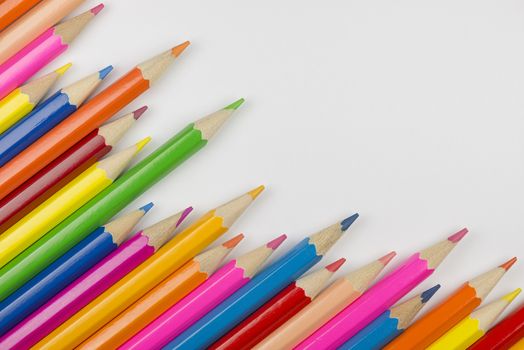 Abstract composition of a set wooden colour pencils against a white background
