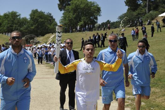 GREECE, Olympia: Greek gymnast and 2015 world champion Lefteris Petrounias carries the Olympic torch at the Temple of Hera on April 21, 2016, during the lighting ceremony of the Olympic flame in ancient Olympia, the sanctuary where the Olympic Games were born in 776 BC. The Olympic flame was lit  in an ancient temple in one country in crisis and solemnly sent off carrying international hopes that Brazil's political paralysis will not taint the Rio Games that start in barely 100 days. 