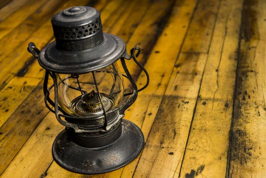 Old oil lantern isolated on wooden floor