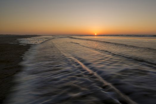 Movement of waves on the beach at sunset
