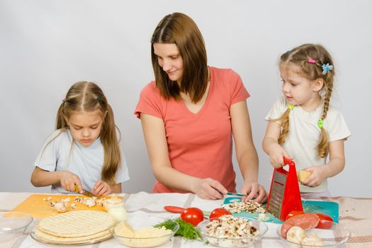 Mum with a five-year daughter watched as the eldest daughter cutting mushrooms pizza