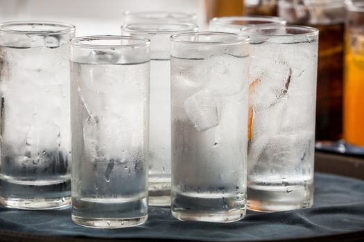 many glass of ice water are on a tray