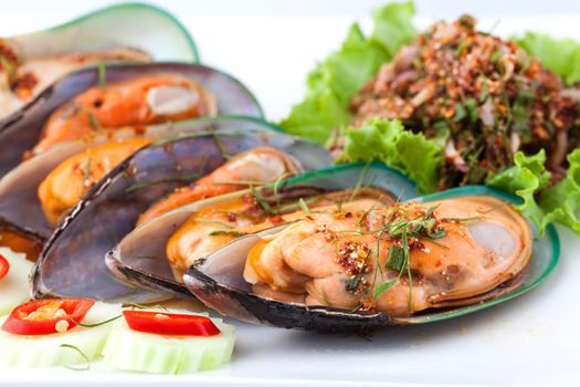 close up of cooked shellfish with spicy salad on white plate