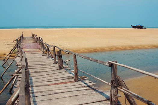 Creative travel photo with blue sky, sea, beach and wood plank road leading far away