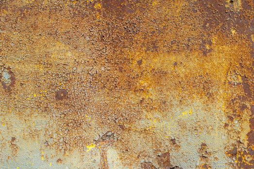 rusty iron surface covered with old chipped yellow color paint, which has long been influenced by different climatic conditions