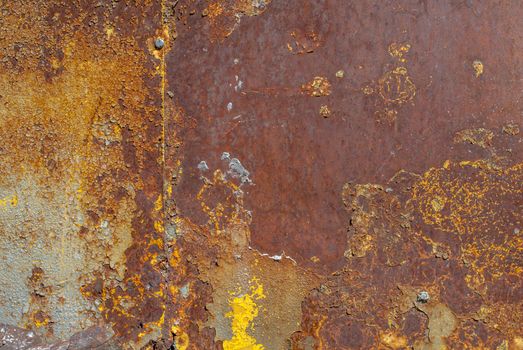 rusty iron surface covered with old chipped yellow color paint, which has long been influenced by different climatic conditions