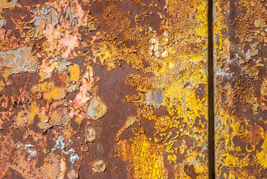 rusty iron surface covered with old chipped yellow color paint, which has long been influenced by different climatic conditions