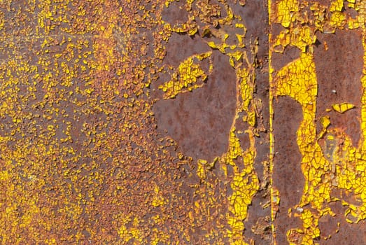 rusty iron surface covered with old chipped yellow color paint, which has long been influenced by different climatic conditions