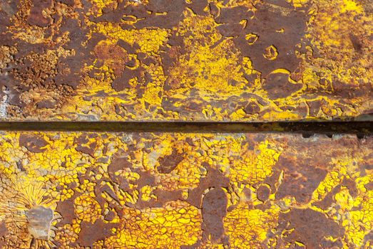 rusty iron surface covered with old chipped yellow color paint, which has long been influenced by different climatic conditions