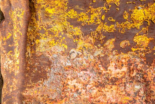 rusty iron surface covered with old chipped yellow color paint, which has long been influenced by different climatic conditions