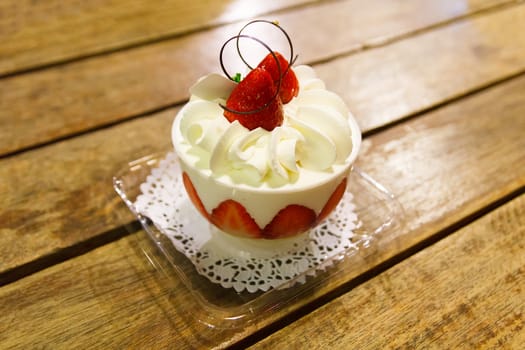 Strawberry cup cake on wooden table.