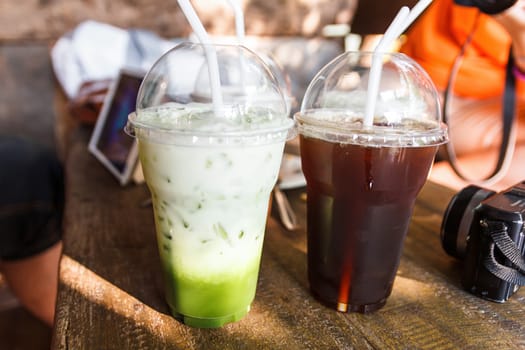 Green tea and iced tea with mirrorless camera and tablet in background.