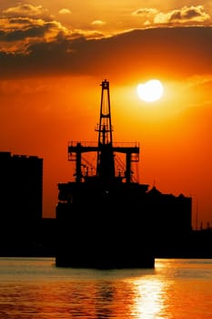 Silhouette picture of vessel with sunset in background.