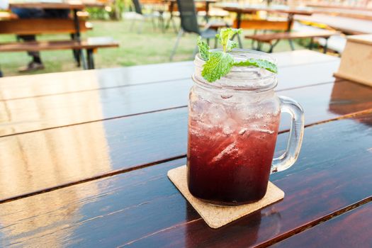 Blueberry soda on wooden table in garden.