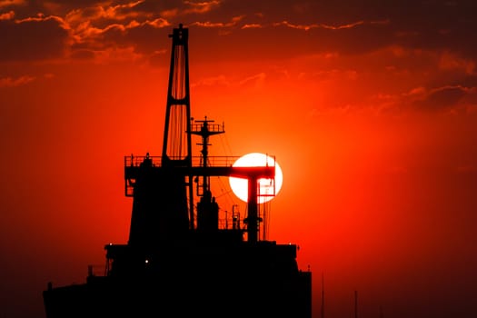Silhouette picture of vessel with sunset in background.