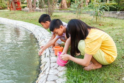 Young Thai children feeding fish in pond.