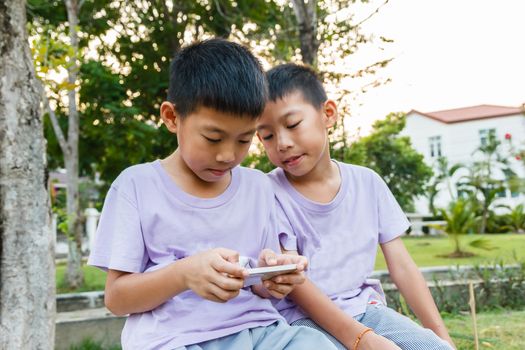 Thai twin boy playing mobile phone.