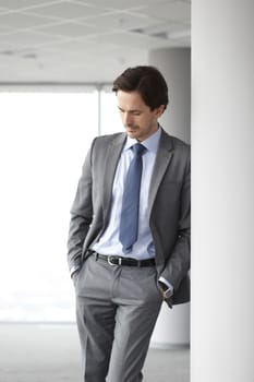 Portrait of handsome businessman standing near windows in office