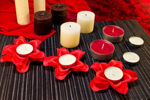 Still life of candles of different shapes on a black and red background