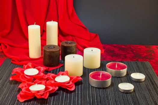 Still life of candles of different shapes on a black and red background