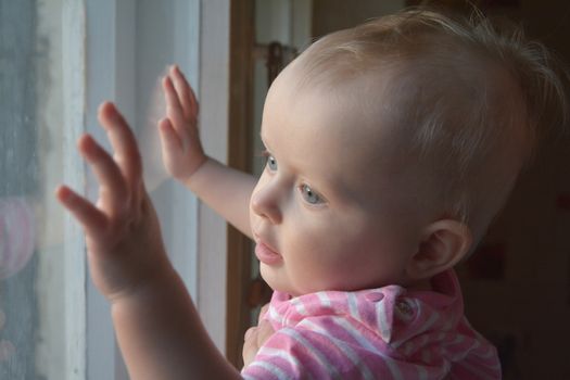 sweet toddler girl looking through the window