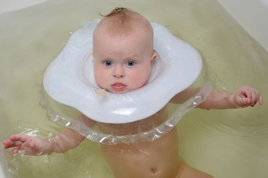 Six month baby swimming with neck swim ring in bath