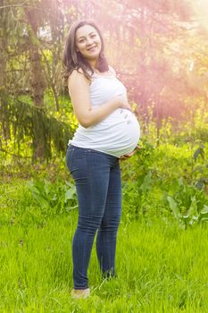 portrait of pregnant young woman outdoors in warm summer day