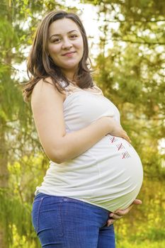portrait of pregnant young woman outdoors in warm summer day