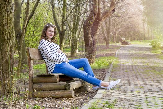 beautiful pregnant woman outdoor in the park on banch