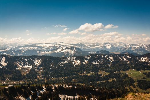 View from Hochgrat in the Alps with snowy peaks on a spring morning in May and blue sky